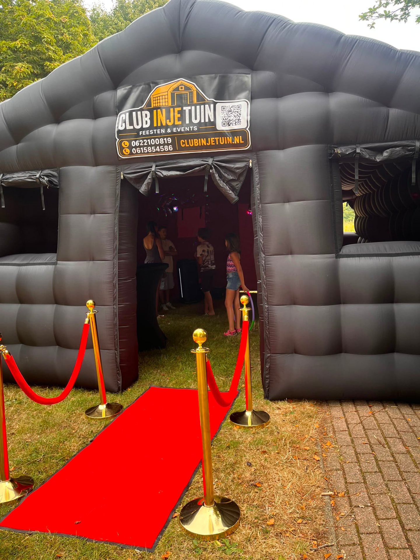 Ingang opblaasbare discotent met rode loper en gouden paaltjes tijdens kinderfeest