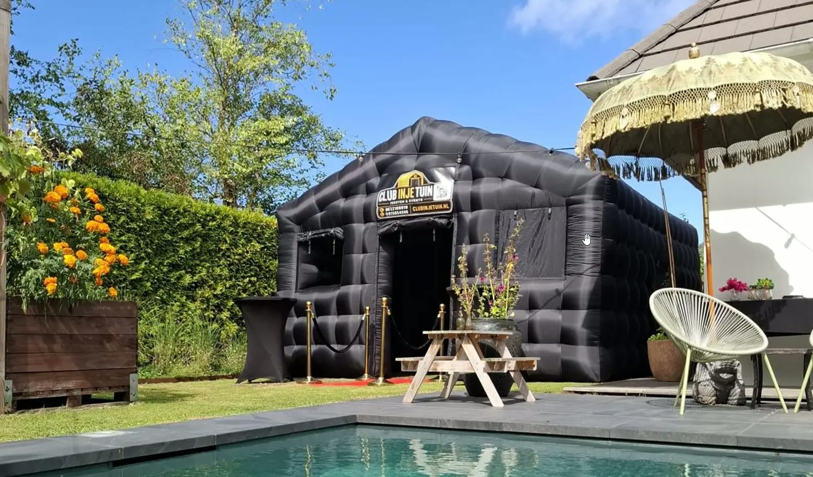 Zwarte opblaasbare discotent met rode loper en gouden paaltjes in tuin in Almere