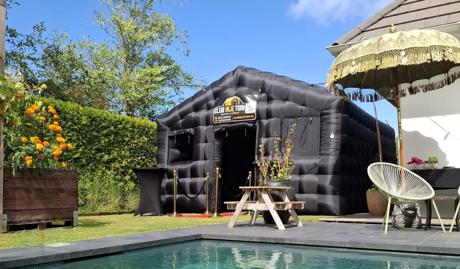 Zwarte opblaasbare discotent met rode loper en gouden paaltjes in tuin in Almere